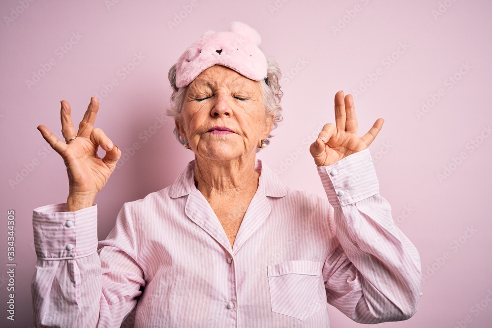 Φωτογραφία Senior beautiful woman wearing sleep mask and pajama over isolated pink background relax and smiling with eyes closed doing meditation gesture with fingers