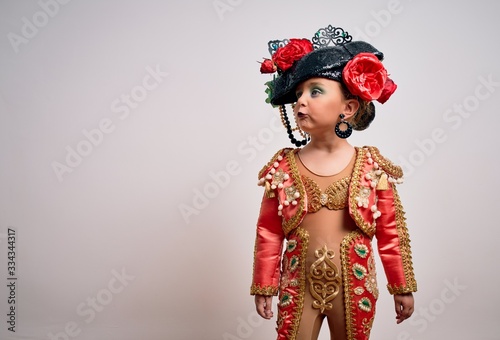 Young little caucasian kid girl wearing bullfighter traditional folkore spanish suit as carnival costume standing over isolated background