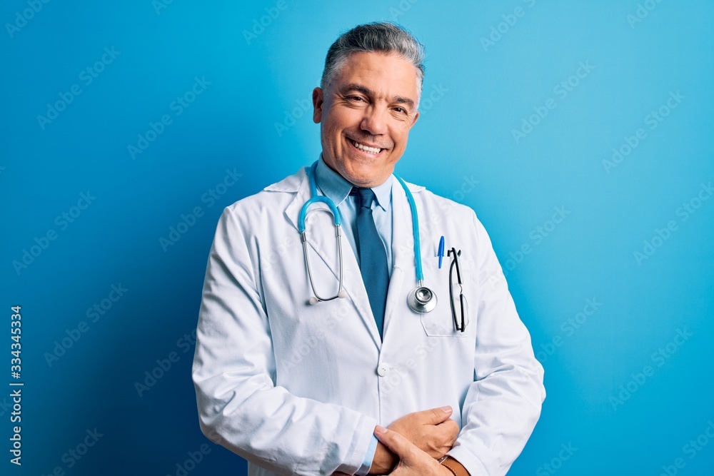 Φωτογραφία Middle age handsome grey-haired doctor man wearing coat and blue stethoscope with hands together and crossed fingers smiling relaxed and cheerful