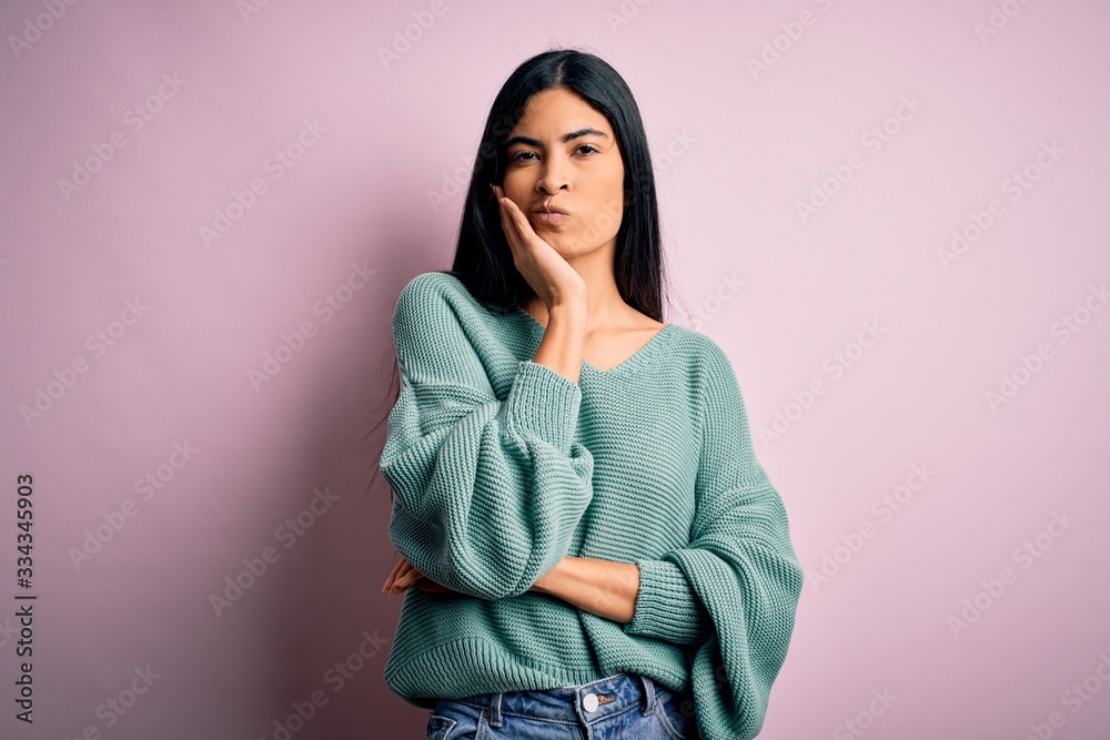 Young beautiful hispanic fashion woman wearing green sweater over pink background thinking looking tired and bored with depression problems with crossed arms. Young beautiful hispanic fashion woman wearing green sweater over pink background thinking looking tired and bored with depression problems with crossed arms.