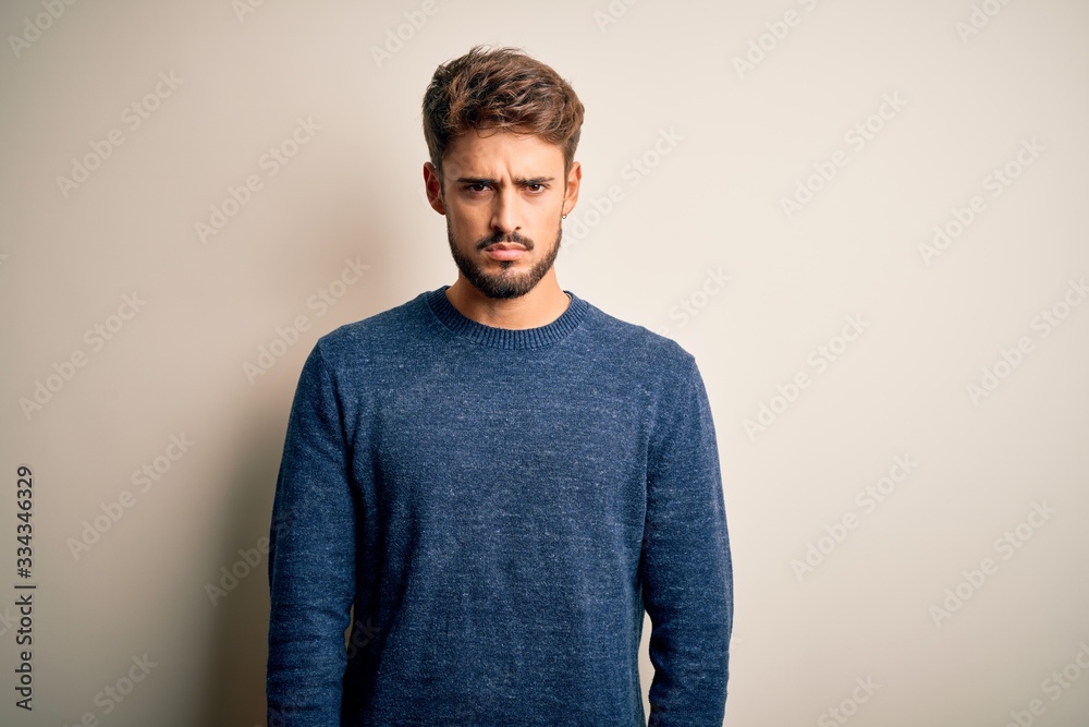Young handsome man with beard wearing casual sweater standing over white background skeptic and nervous, frowning upset because of problem. Negative person. Young handsome man with beard wearing casual sweater standing over white background skeptic and nervous, frowning upset because of problem. Negative person.