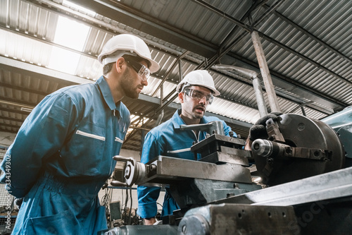 Engineer men wearing uniform safety in factory working machine lathe metal.
