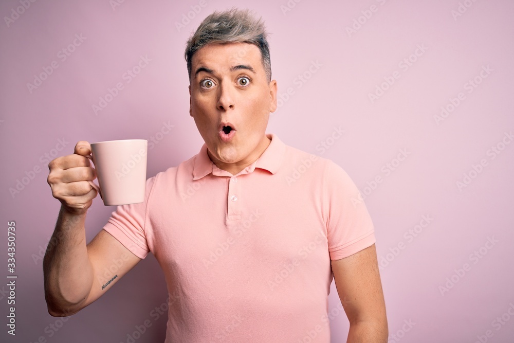 Young modern handsome man drinking a cup of hot coffee over isolated pink background scared in shock with a surprise face, afraid and excited with fear expression Young modern handsome man drinking a cup of hot coffee over isolated pink background scared in shock with a surprise face, afraid and excited with fear expression