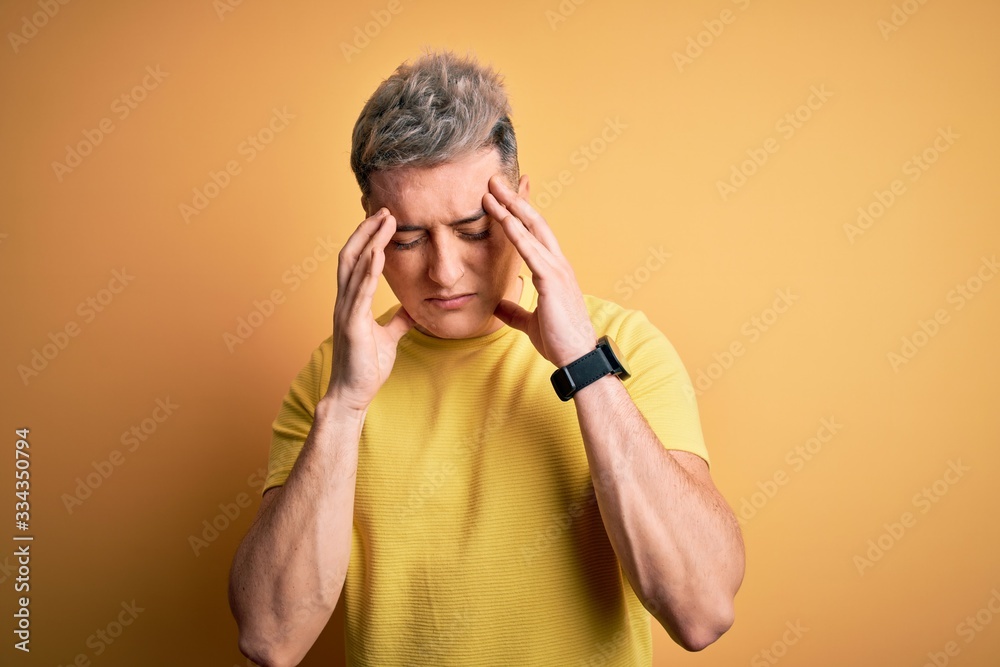 Young handsome modern man wearing yellow shirt over yellow isolated background with hand on headache because stress. Suffering migraine. Young handsome modern man wearing yellow shirt over yellow isolated background with hand on headache because stress. Suffering migraine.