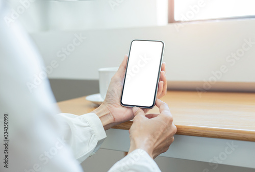 cell phone Mockup image blank white screen.woman hand holding texting using mobile on desk at coffee shop.background empty space for advertise text.people contact marketing business,technology