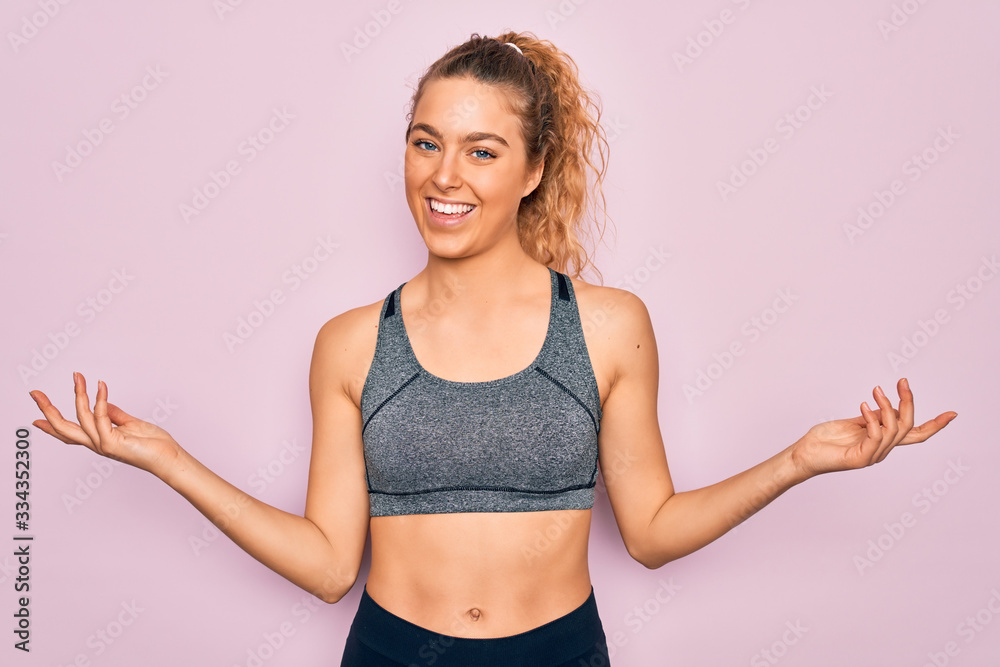 Young beautiful blonde sportswoman with blue eyes doing exercise wearing sportswear smiling showing both hands open palms, presenting and advertising comparison and balance
