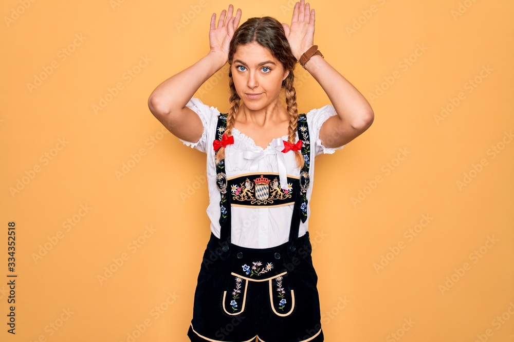 Young beautiful blonde german woman with blue eyes wearing traditional octoberfest dress Doing bunny ears gesture with hands palms looking cynical and skeptical. Easter rabbit concept. Young beautiful blonde german woman with blue eyes wearing traditional octoberfest dress Doing bunny ears gesture with hands palms looking cynical and skeptical. Easter rabbit concept.