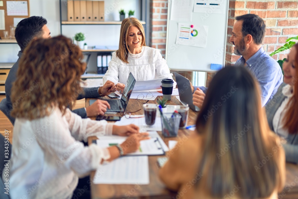 Group of business workers working together. Sitting on desk using laptop reading documents at the office Group of business workers working together. Sitting on desk using laptop reading documents at the office