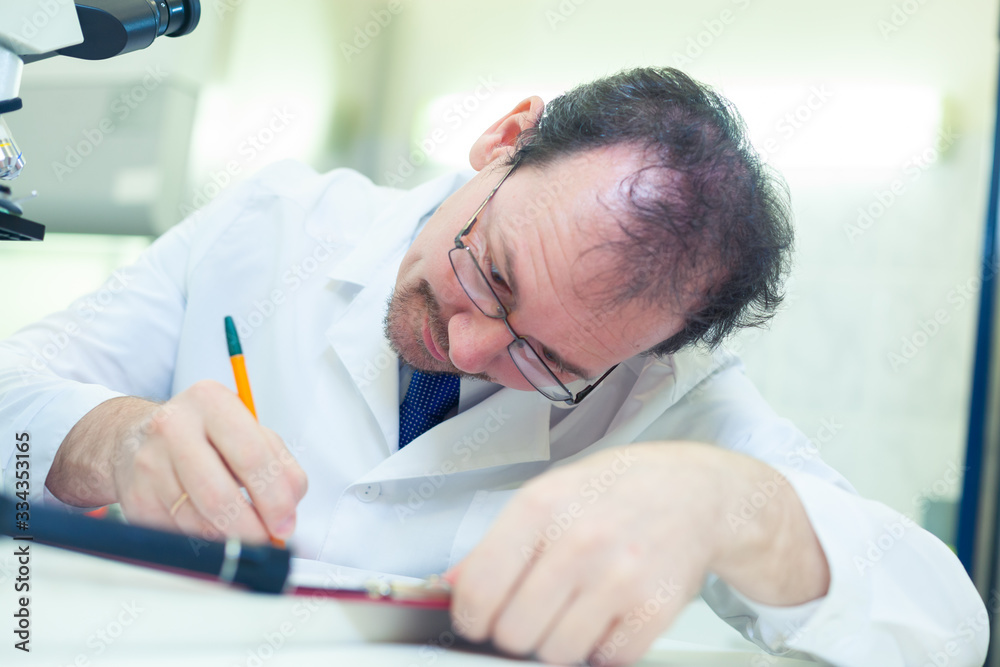 Naklejka premium Chemist crazy. A mad scientist conducts experiments in a scientific laboratory. Intently records the results of the study. COVID-19. COVID Coronavirus