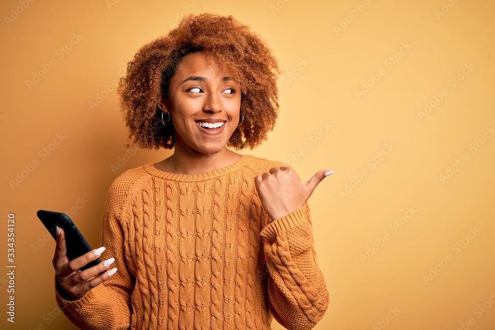 Young African American afro woman with curly hair having conversation using smartphone pointing and showing with thumb up to the side with happy face smiling Young African American afro woman with curly hair having conversation using smartphone pointing and showing with thumb up to the side with happy face smiling