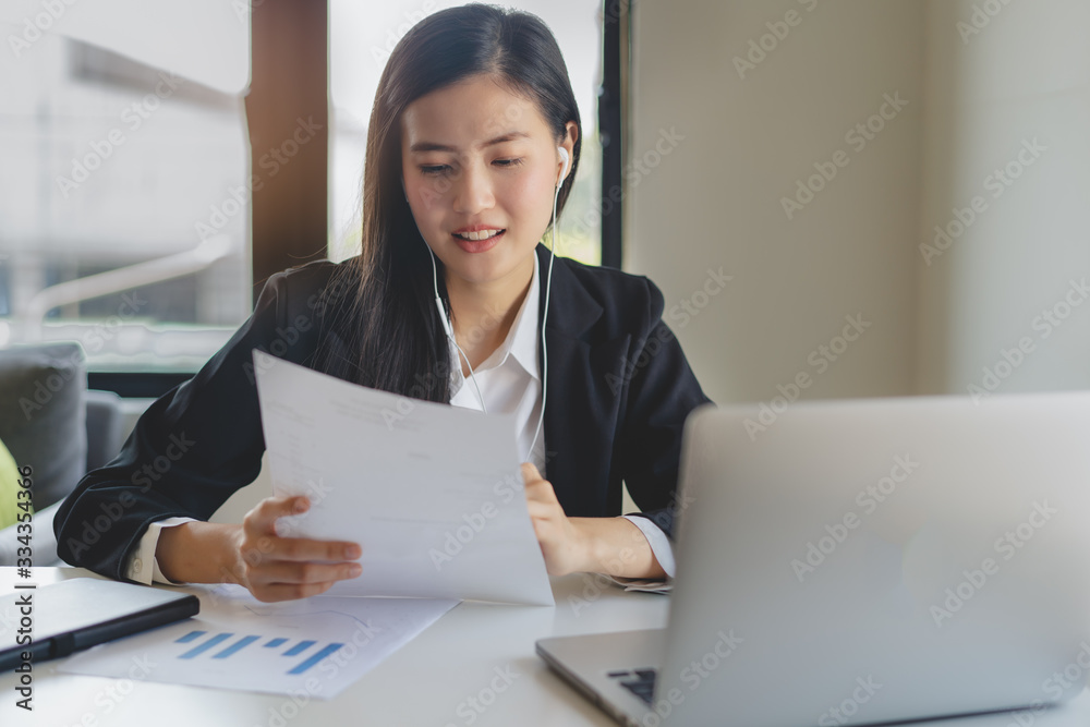Working from home using internet communication concept. Asian young woman wear earphones talking in video conference with business partners and worker team via online internet at her home. Working from home using internet communication concept. Asian young woman wear earphones talking in video conference with business partners and worker team via online internet at her home.