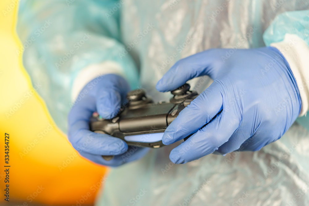 Man in a protective medical suit and gloves with a gamepad. video games and gaming during quarantine, self-isolation. COVID-19 pandemic coronavirus. stay home