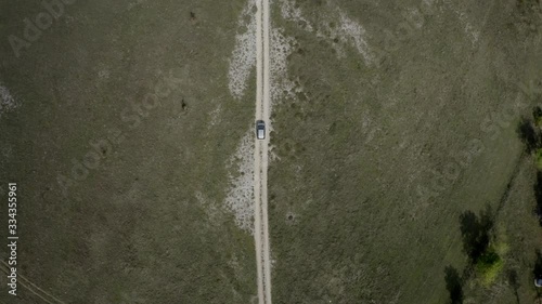 Aerial top down view of car driving on rural road, path in the field. Countryside. Rural landscape. Village in Montenegro.