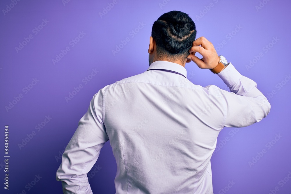 Young brazilian businessman wearing elegant tie standing over isolated purple background Backwards thinking about doubt with hand on head