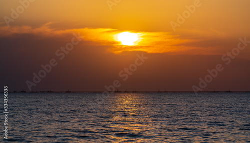Colorful sunrise at sea, oil platforms in distance