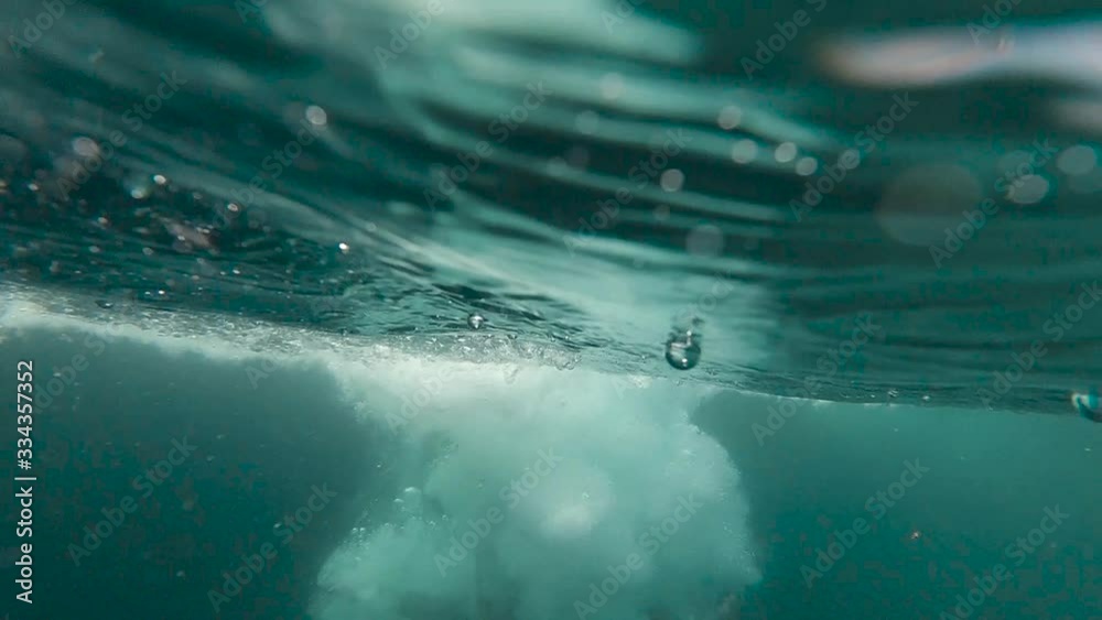 Slow motion 240 FPS underwater shot of water splashes in the sea after a man jumps from cliffs inside the sea
