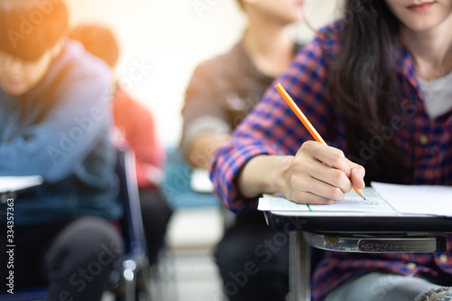 high school,university student study.hands holding pencil writing paper answer sheet.sitting lecture chair taking final exam attending in examination classroom.concept scholarship for education abroad photo
