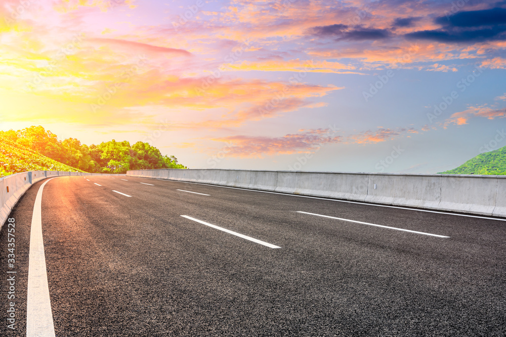 Empty asphalt road and green tea plantation nature landscape at sunset.