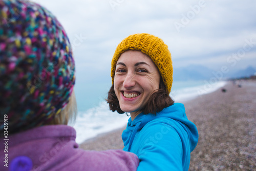 Two smiling girls hug each other on the beach.