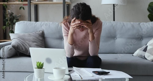 Stressed worried young woman feels panic about financial problem checking household payments. Frustrated female renter calculating bills, bank mortgage debt looking desperate about bankruptcy at home. photo
