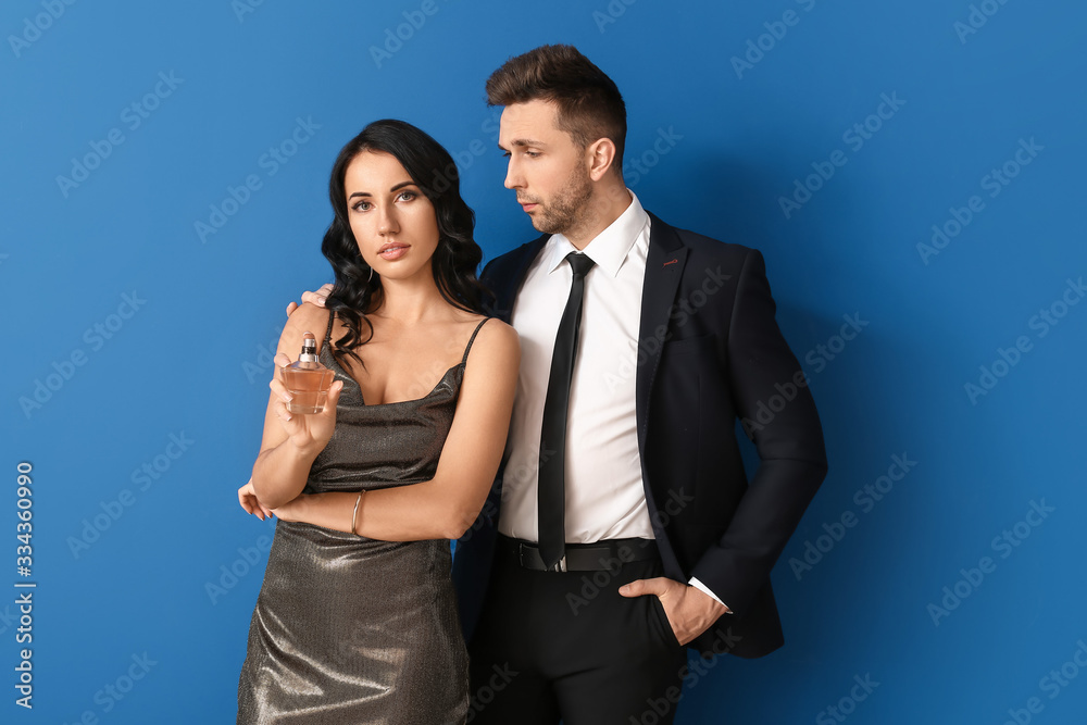 Stylish young couple with perfume on color background Stylish young couple with perfume on color background