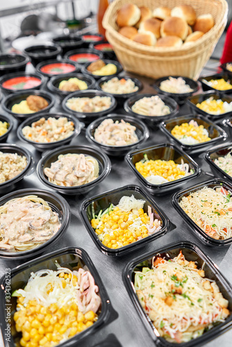 Food delivery. Different in plastic disposable lunch box with healthy natural food. Chicken broth, mashed soup, mashed potatoes with cutlet, seafood pasta, salads, pilaf with a fresh bun.