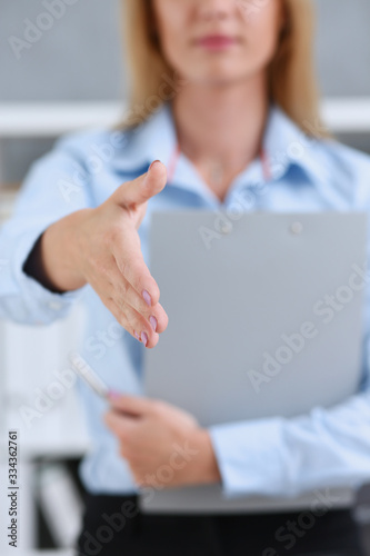 Businesswoman offer hand to shake as hello in office closeup. Serious business friendly support service excellent prospect introduction or thanks gesture gratitude invite to participate concept