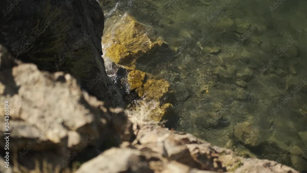 view from edge of cliff on water below, water hits rocks, lake in Mongolia view from edge of cliff on water below, water hits rocks, lake in Mongolia