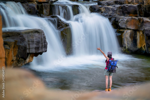 Woman traveller backpacker enjoy motion sightseeing to see jungle waterfalls in rainforest tropical at summertime and long weekend vacation trip, disconnected and away from the place of crowd