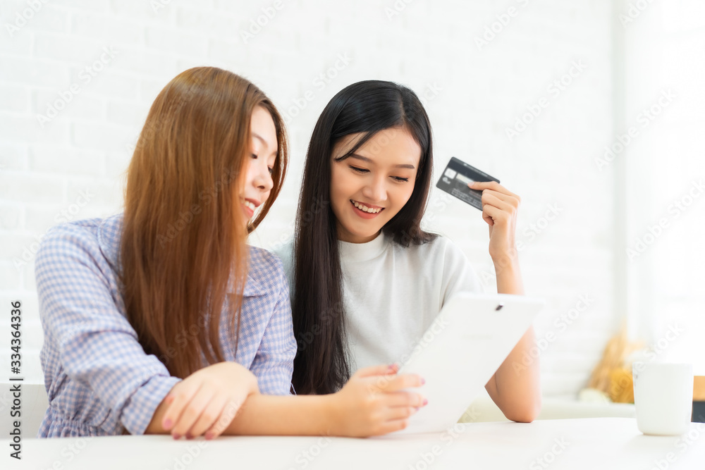 Happy best friends laughing during watching funny videos on internet social media life . Young Asian female doing online shopping through laptop and credit card at home. Happy best friends laughing during watching funny videos on internet social media life . Young Asian female doing online shopping through laptop and credit card at home.