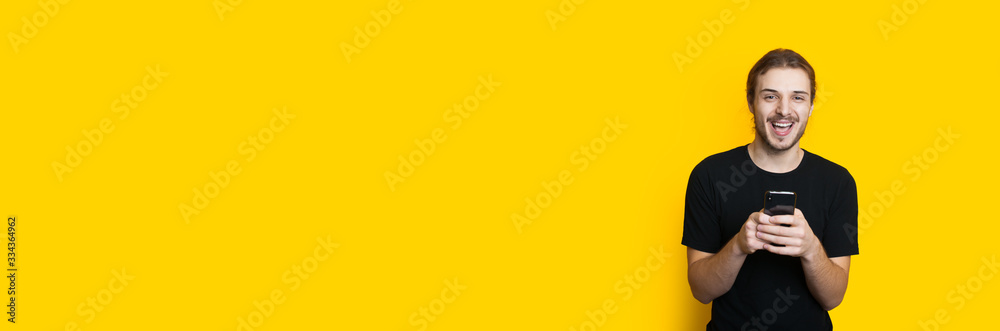 Happy caucasian man with beard and long hair is chatting with somebody on a yellow background with empty space Happy caucasian man with beard and long hair is chatting with somebody on a yellow background with empty space
