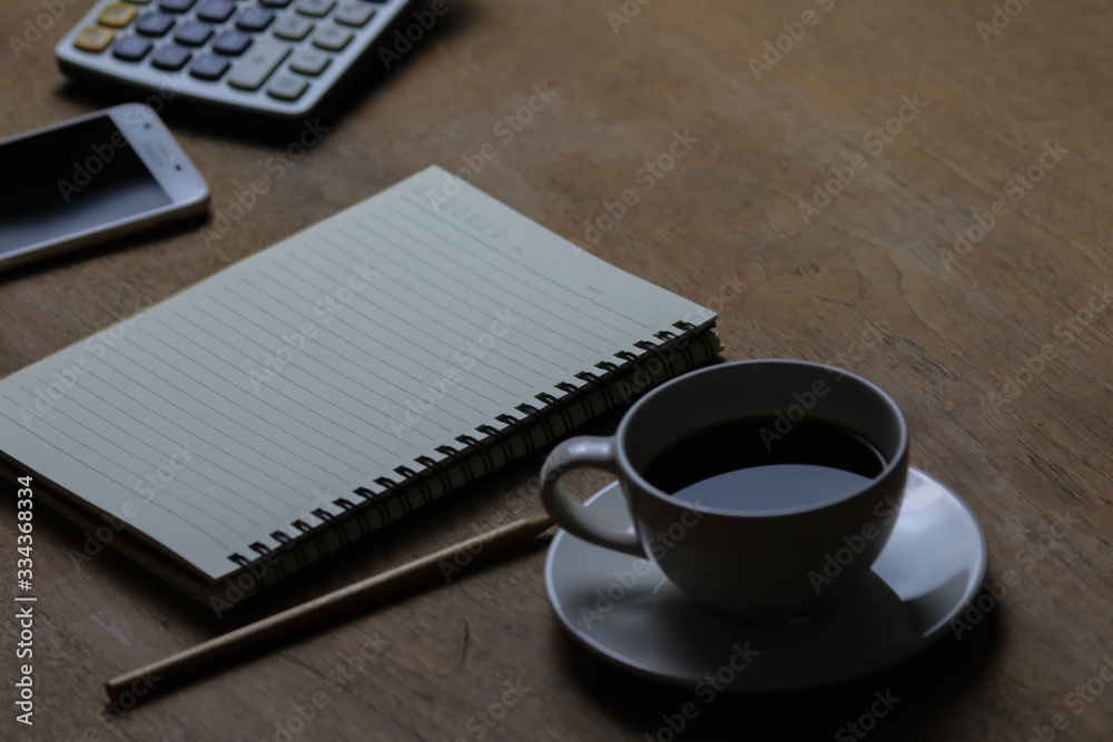 Notebook, white coffee cup and pencil on wooden table. Selective focus. Notebook, white coffee cup and pencil on wooden table. Selective focus.