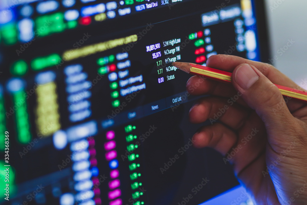 Business man hand holding pencil points to stock market graph analysis on monitor screen. Economic and financial concept. Seletive focus. Business man hand holding pencil points to stock market graph analysis on monitor screen. Economic and financial concept. Seletive focus.