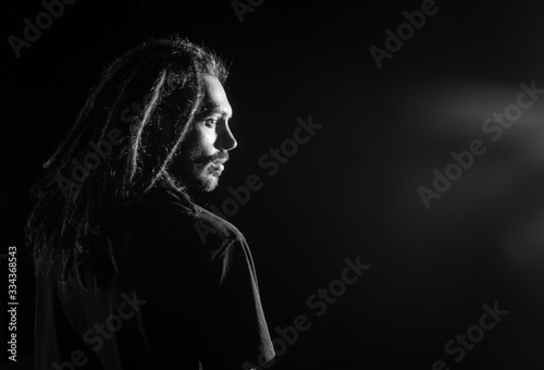 Male person with dreadlocks at dark background