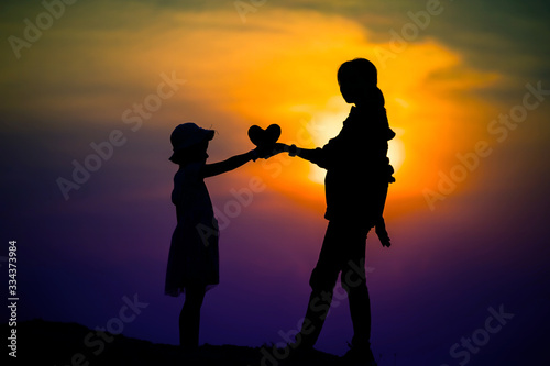 silhouette of a family with a happy mother playing with a girl in the sunset sky © stcom