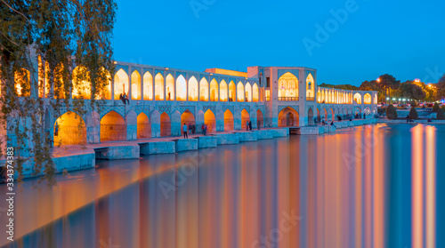 People resting in the ancient Khaju Bridge at twilight blue hour - Isfahan, Iran