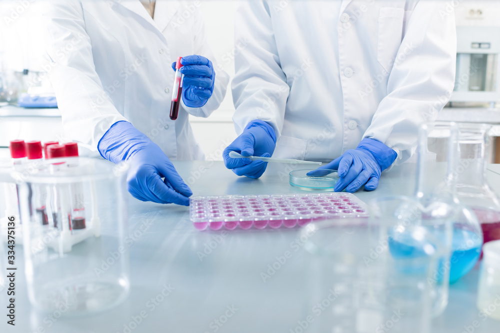 Gloved hands of two contemporary scientists testing new sanitizer or vaccine Gloved hands of two contemporary scientists testing new sanitizer or vaccine