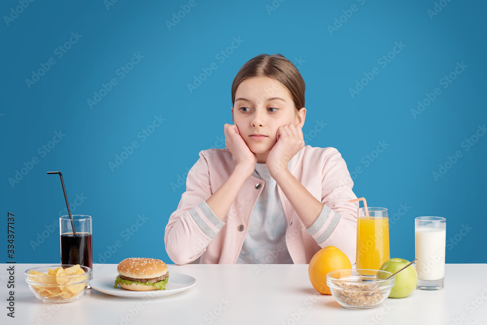 Teenage girl choosing between fresh organic healthy eating and junk food Teenage girl choosing between fresh organic healthy eating and junk food