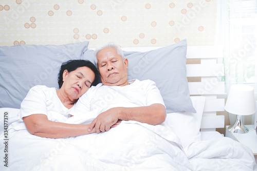 Asian elderly couple Sleep in bed in the bedroom. Senior health concepts, illness, retirement life. copy space