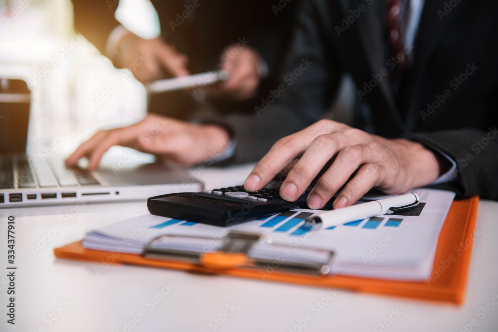 Close up Businessman and partner using calculator and laptop for calculation finance, tax, accounting, statistics and analytic research concept. in the office. Close up Businessman and partner using calculator and laptop for calculation finance, tax, accounting, statistics and analytic research concept. in the office.