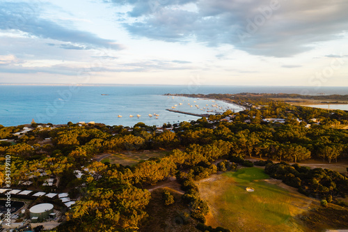 Aerial drone image of Rottnest Island during a beautiful golden sunset. The bays on the remote island can be seen with the settlement below. 