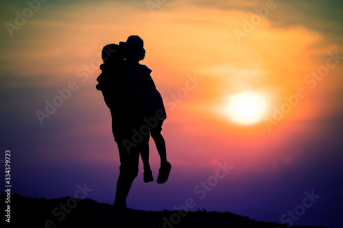 silhouette of a family with a happy mother playing with a girl in the sunset sky