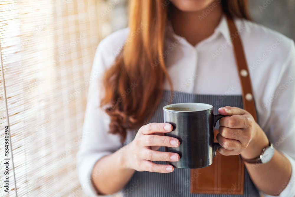 A waitress holding and serving a cup of hot coffee in cafe A waitress holding and serving a cup of hot coffee in cafe