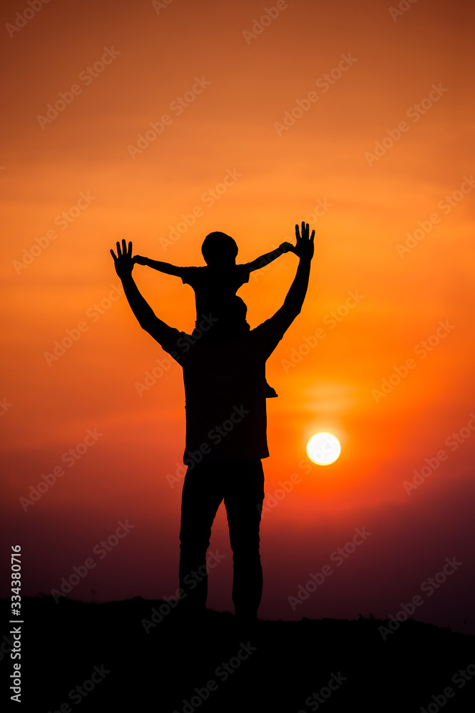 silhouette of a family with a boy riding his father's neck happily against the sunset sky silhouette of a family with a boy riding his father's neck happily against the sunset sky