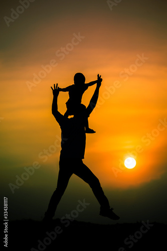 silhouette of a family with a boy riding his father's neck happily against the sunset sky