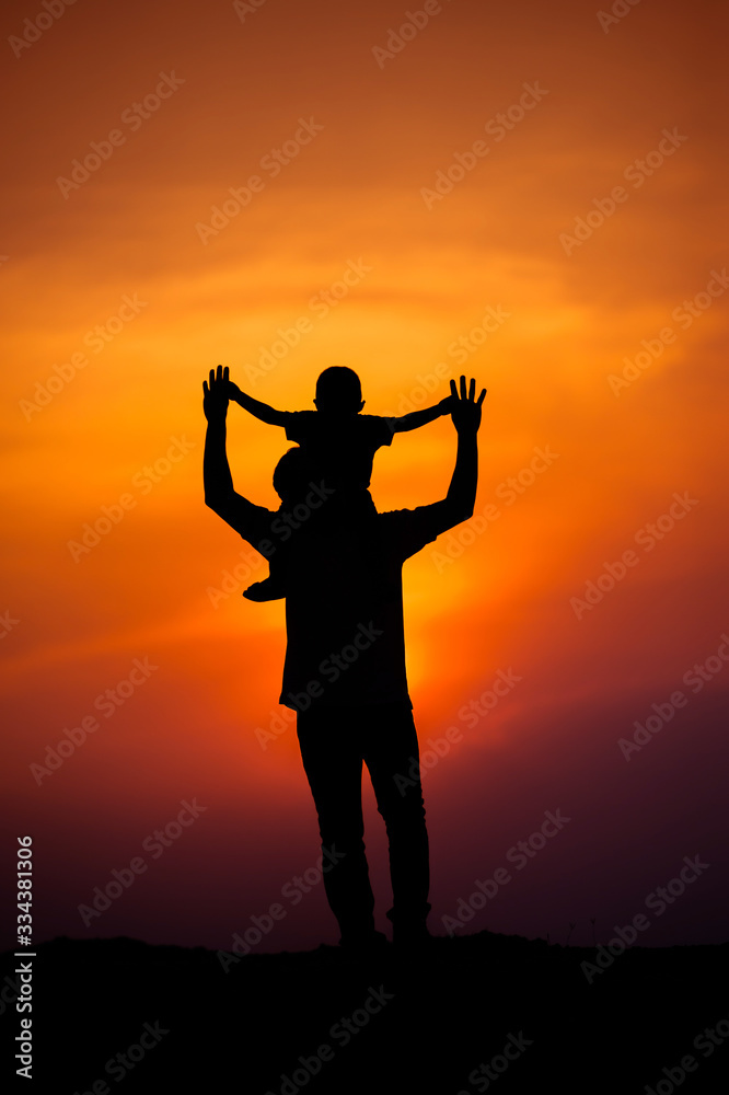 silhouette of a family with a boy riding his father's neck happily against the sunset sky