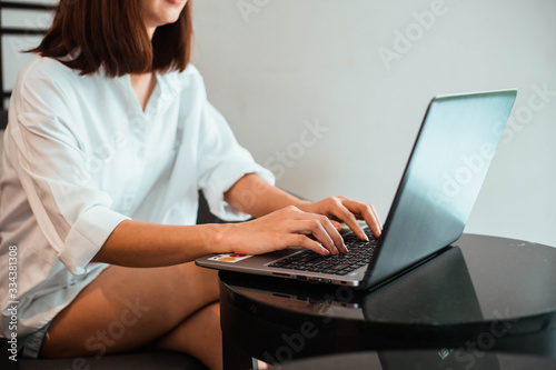 young woman working on laptop computer while sitting at the living room. work from home concept