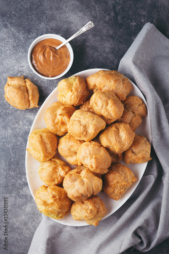 Obraz na plátne Top view on profitroles on white plate and caramel on stone table with napkin