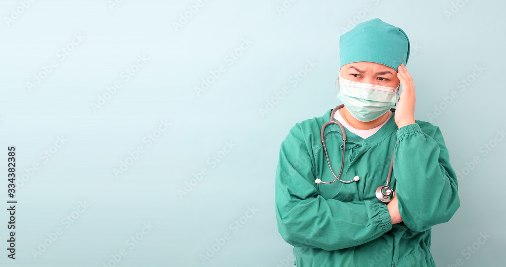 female asia surgeon,surgeon Feeling anxious, showing stethoscope wearing protective mask infectious diseas and coronavirus or covid-19, on a blue background in studio With copy space. female asia surgeon,surgeon Feeling anxious, showing stethoscope wearing protective mask infectious diseas and coronavirus or covid-19, on a blue background in studio With copy space.