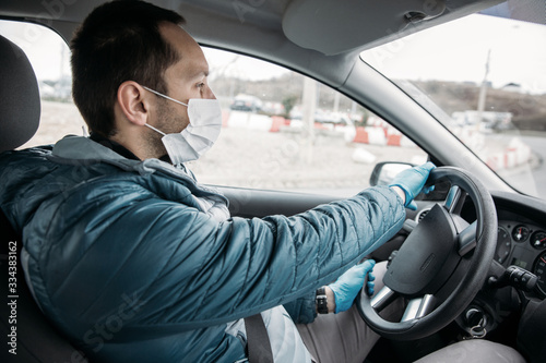 Man driving in a car with protective mask and gloves. Covid-19 concept image.  © belyaaa